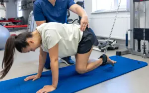 Fisioterapeuta evaluando atleta con lesión. Obtén tu titulación y mejora tu empleabilidad.